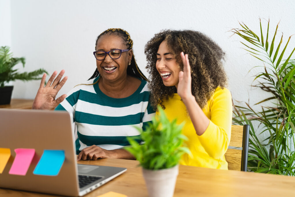 Happy African mother and daughter greeting the family in online